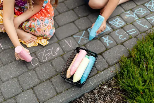 I bambini disegnano con i gessetti colorati sul marciapiede all’aperto.